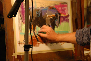 A man draws an abstract and colorful bull with oil pastels