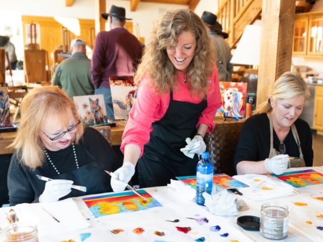 Artist Carol Hagan teaching a guest how to paint.