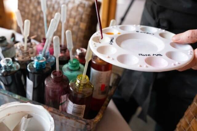 Artist placing drops of paint on her pallet board.