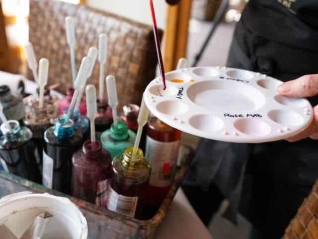 Artist placing drops of paint on her pallet board.