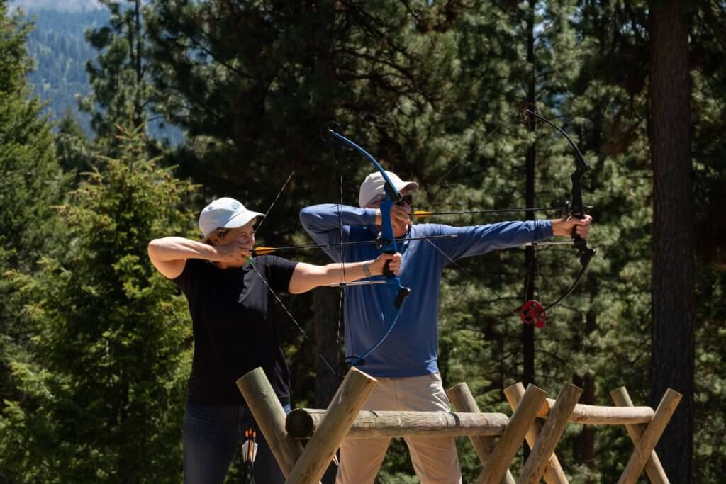 Guests with bows trying to shoot an archery target.