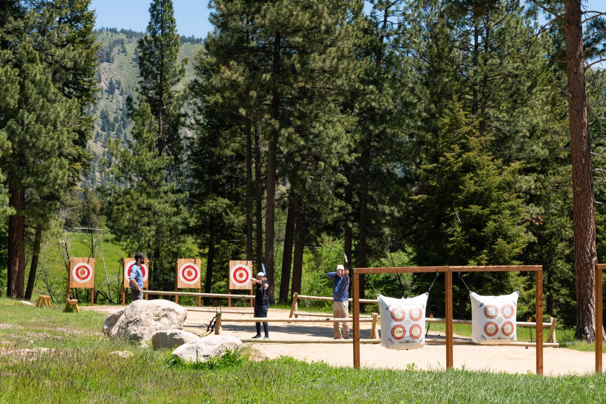 Guests with bows trying to shoot an archery target.
