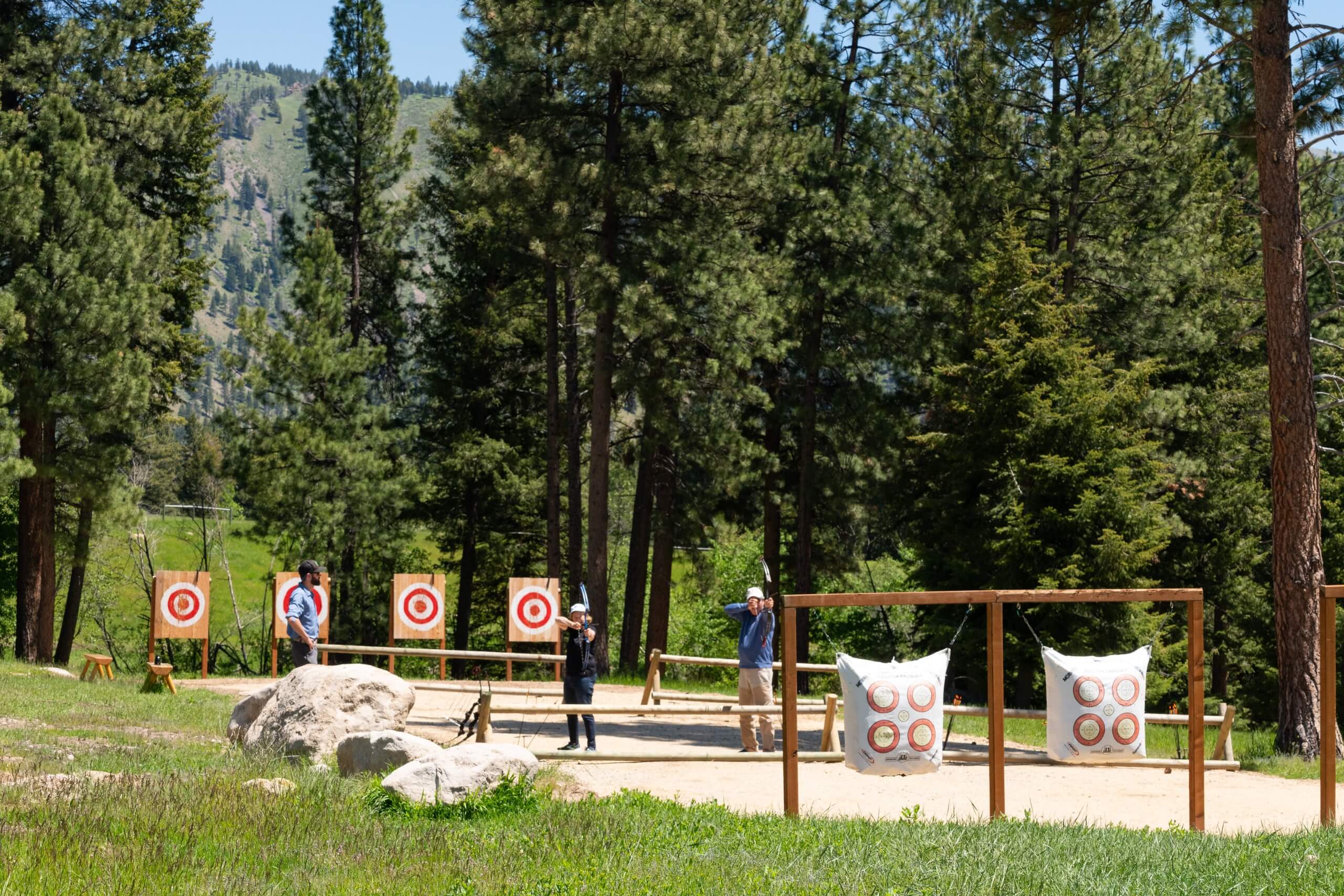 Guests with bows trying to shoot an archery target.