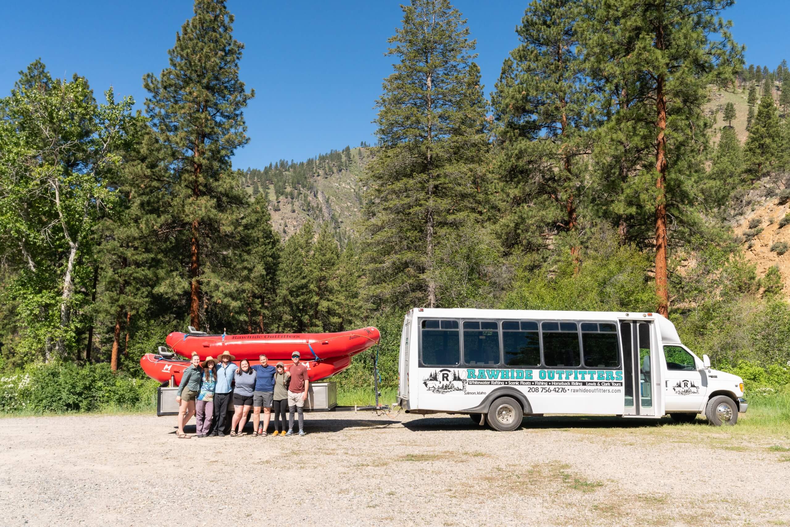 Guests standing in front of rafts and bus while waiting to go white water rafting.