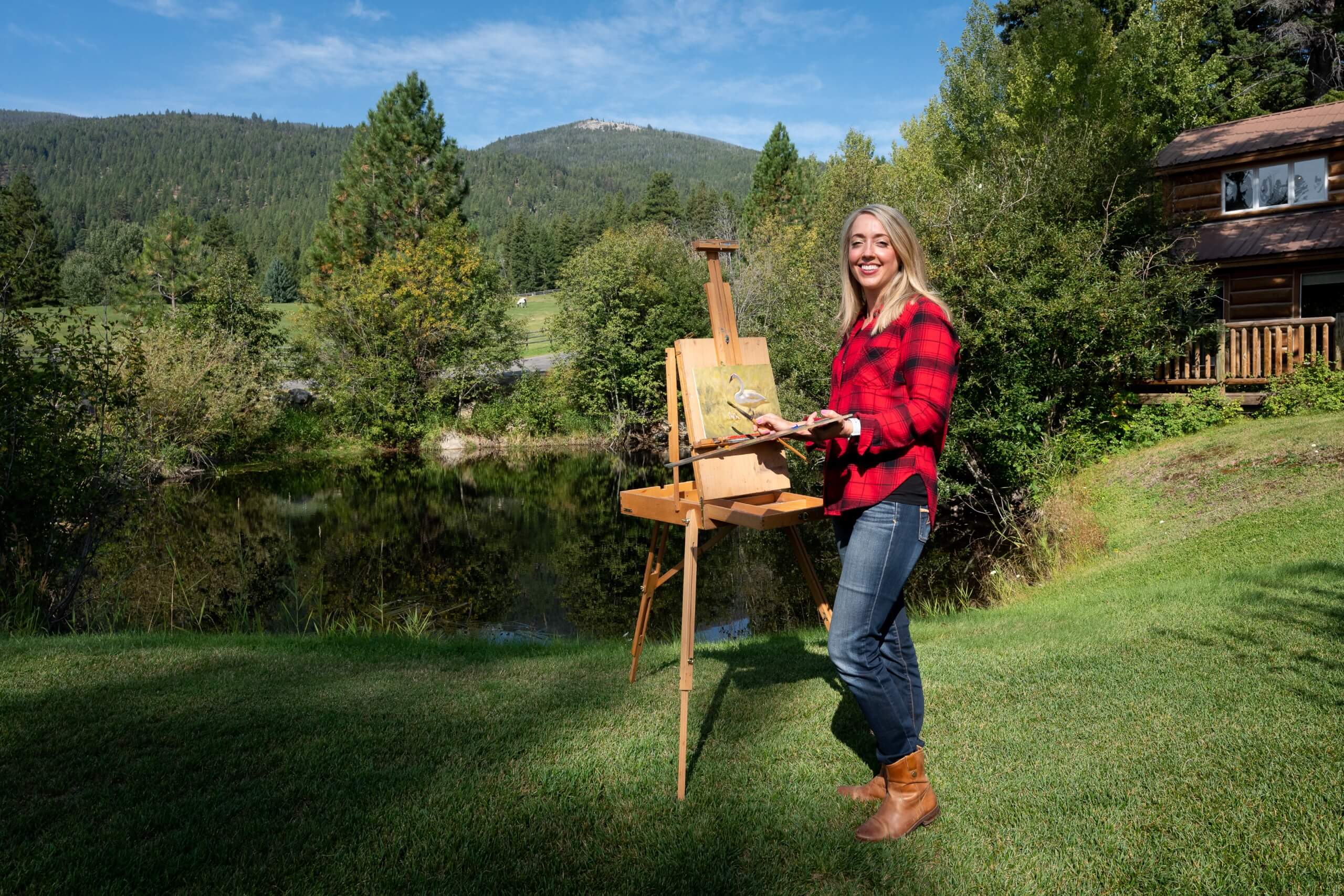 Sally Vannoy painting by the pond with mountains in the background.