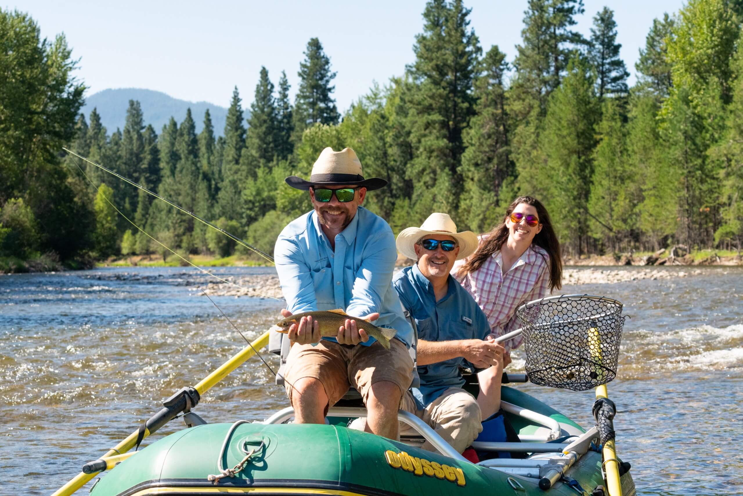 Guests caught a fish while fly fishing on the west fork river with the bitterroot mountains in the background.