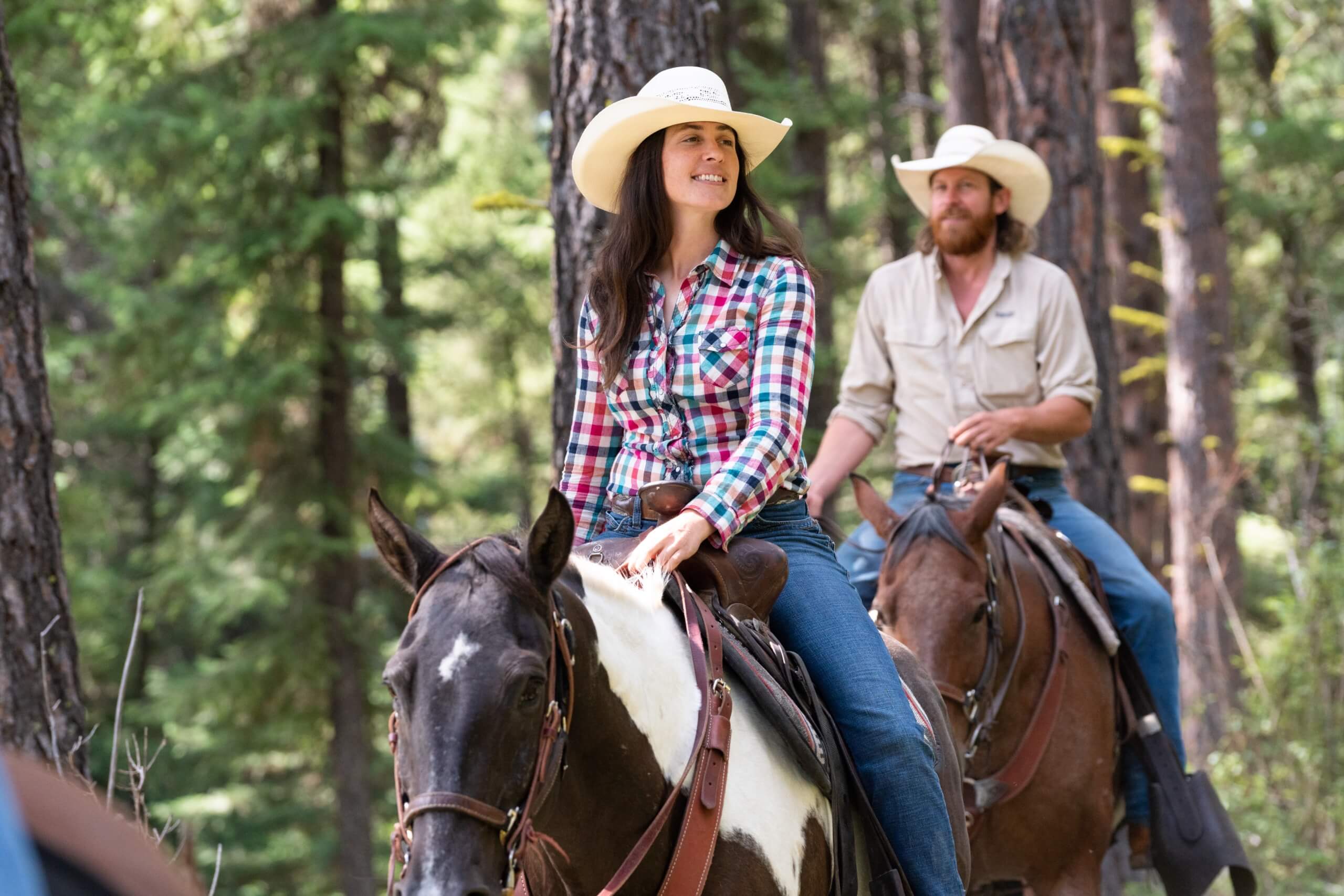 Guests horseback riding through the forest.