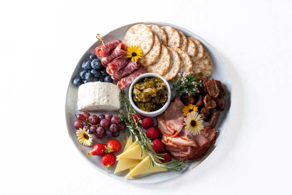 Cheese, fruit, and meat on a plate.