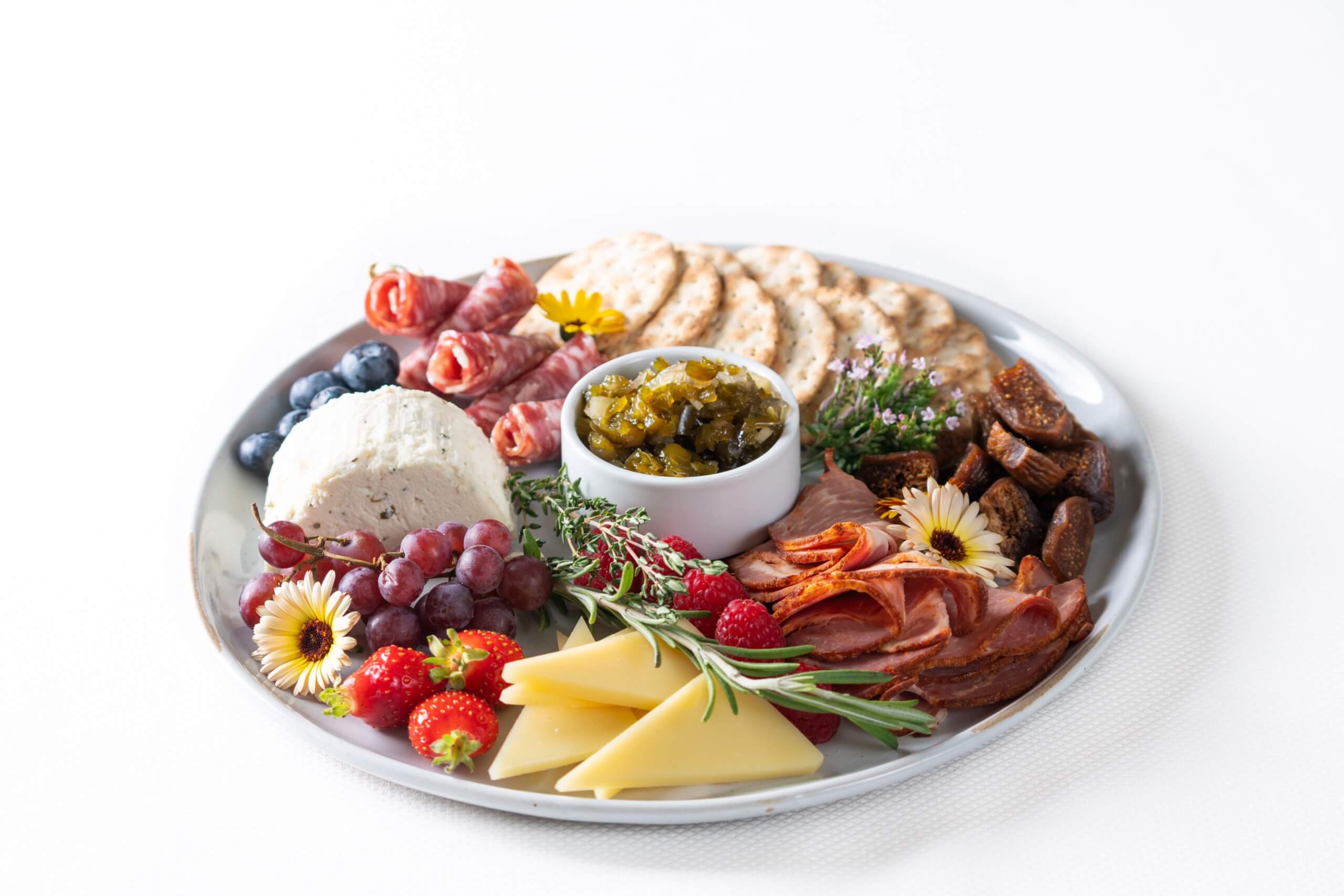 Cheese, fruit, and meat on a plate.