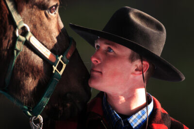 Cowboy looking at horse.