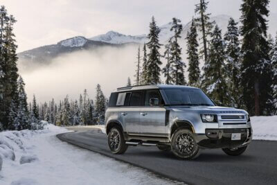 A silver SUV on a mountain road. Snow on the ground and fog in the air